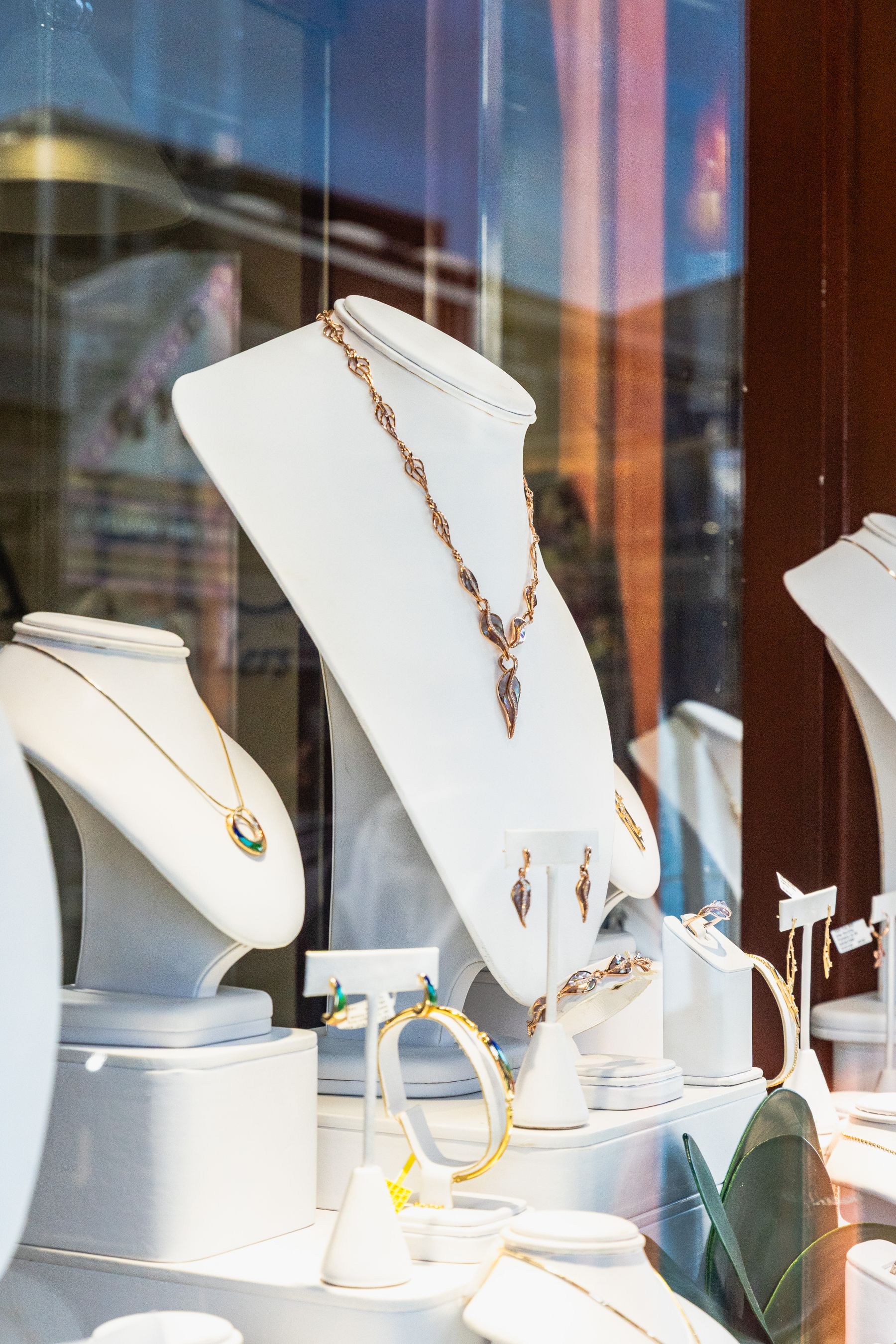 Jewelry storefront window with necklaces on white display busts