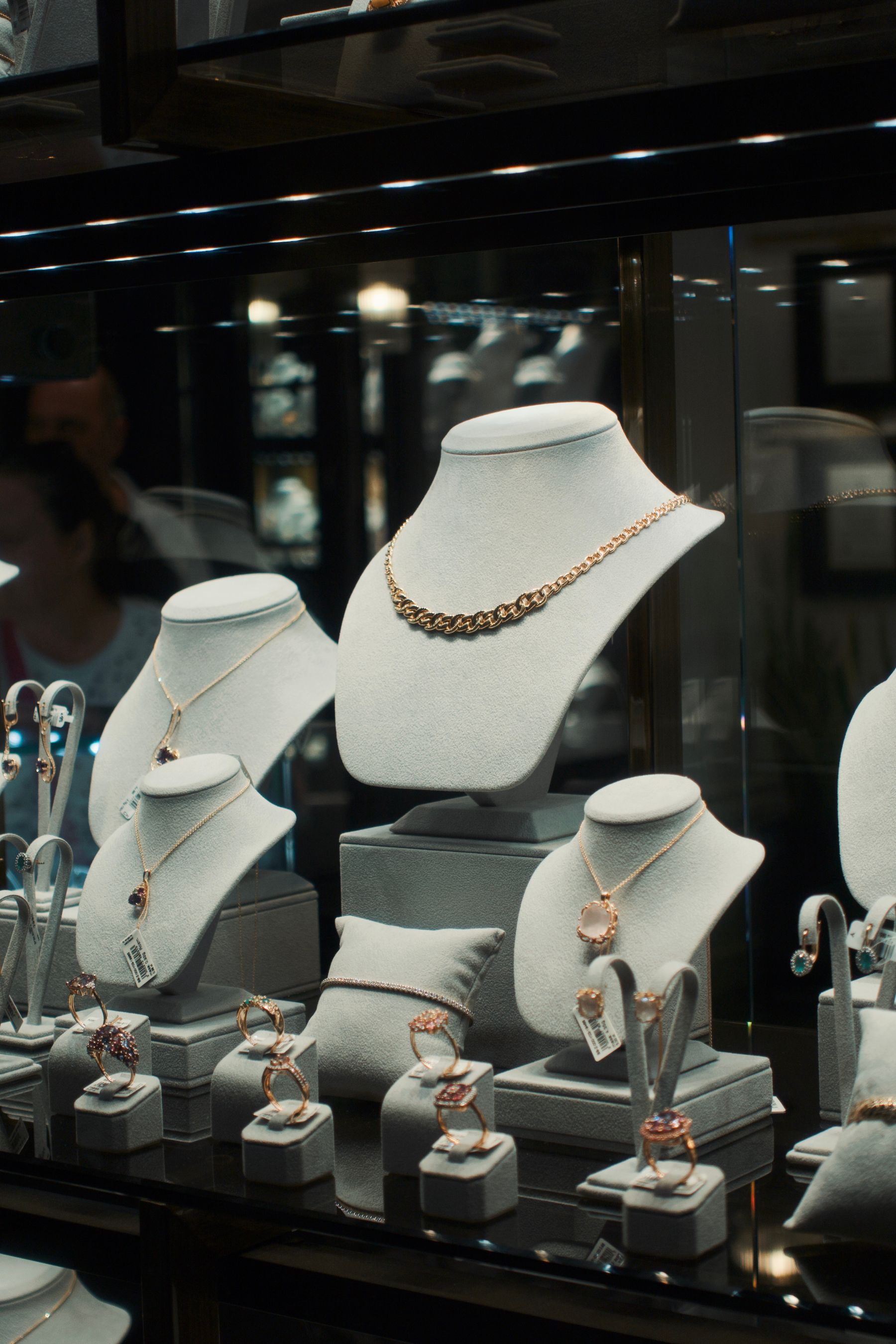 Necklaces on busts inside a dark glass jewelry case