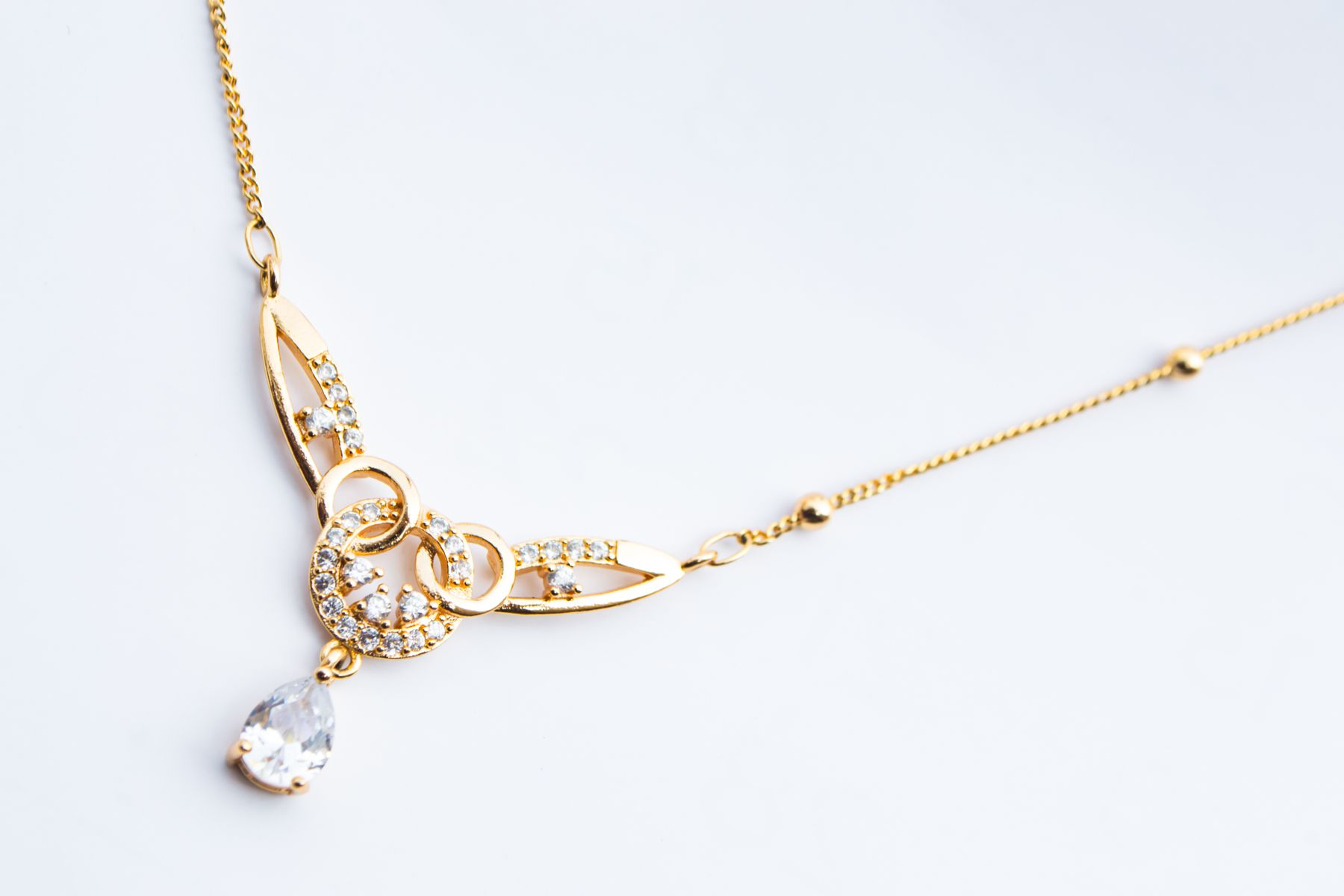 Gold pendant necklace laid on a white surface